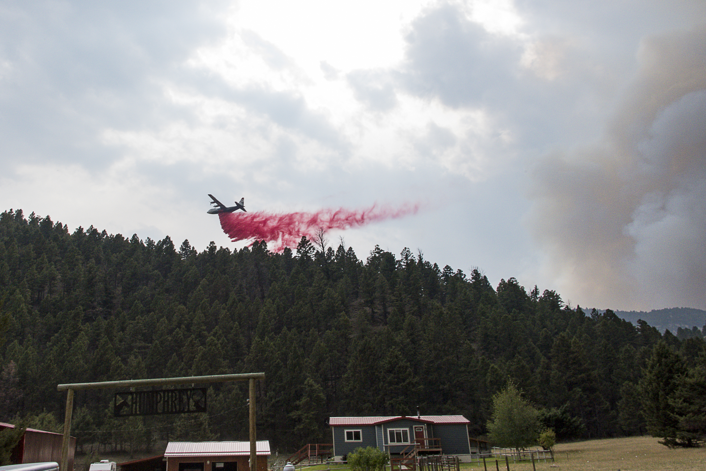 <p>An air tanker drops fire retardant on a ridgeline along the south side of Cattle Drive Lane, just